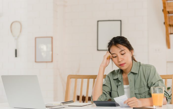 Business Asian women records of income and expenses at home You woman calculating income and expenses at home