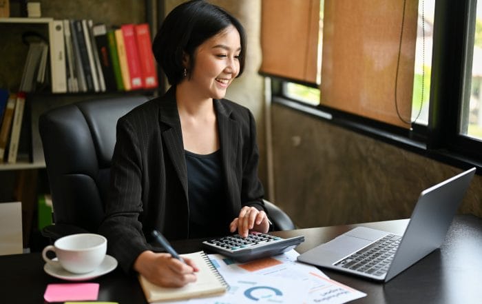 Happy Asian businesswoman is satisfied with her business income while calculating sales